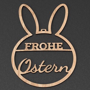 Może przedstawiać: Drewniany wycinany kr&oacute;lik wielkanocny z tekstem "Frohe Ostern" w języku niemieckim.