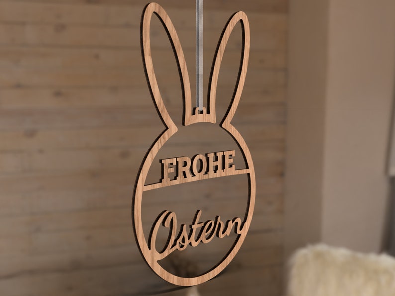 Może przedstawiać: Drewniana ozdoba wielkanocna w kształcie kr&oacute;lika z napisem "Frohe Ostern" w k&oacute;łku.