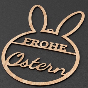 Może przedstawiać: Drewniana ozdoba wielkanocna w kształcie kr&oacute;lika z napisem "Frohe Ostern" w języku niemieckim.