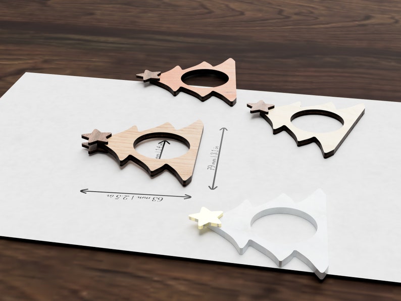 May include: Four wooden Christmas tree napkin rings in different shades of brown and white. The rings are 6.9 cm (2.7 inches) wide and 7.2 cm (2.8 inches) tall.