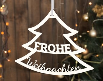 Könnte beinhalten: Weißer Holz-Weihnachtsbaum-Anhänger mit dem Text "Frohe Weihnachten" vor einem verschwommenen Hintergrund eines Weihnachtsbaums mit Lichtern.