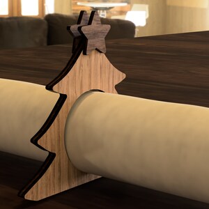 May include: Wooden Christmas tree napkin ring with two star accents. The ring is made of light brown wood and has a natural wood grain finish.