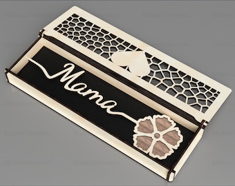 May include: A wooden box with a cutout design on the lid. The box is open and the inside is lined with black felt. The word "Mama" is written on the felt. A small wooden flower is inside the box.