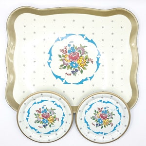 May include: A white metal serving tray with a gold rim and a floral design. The tray comes with two matching coasters.