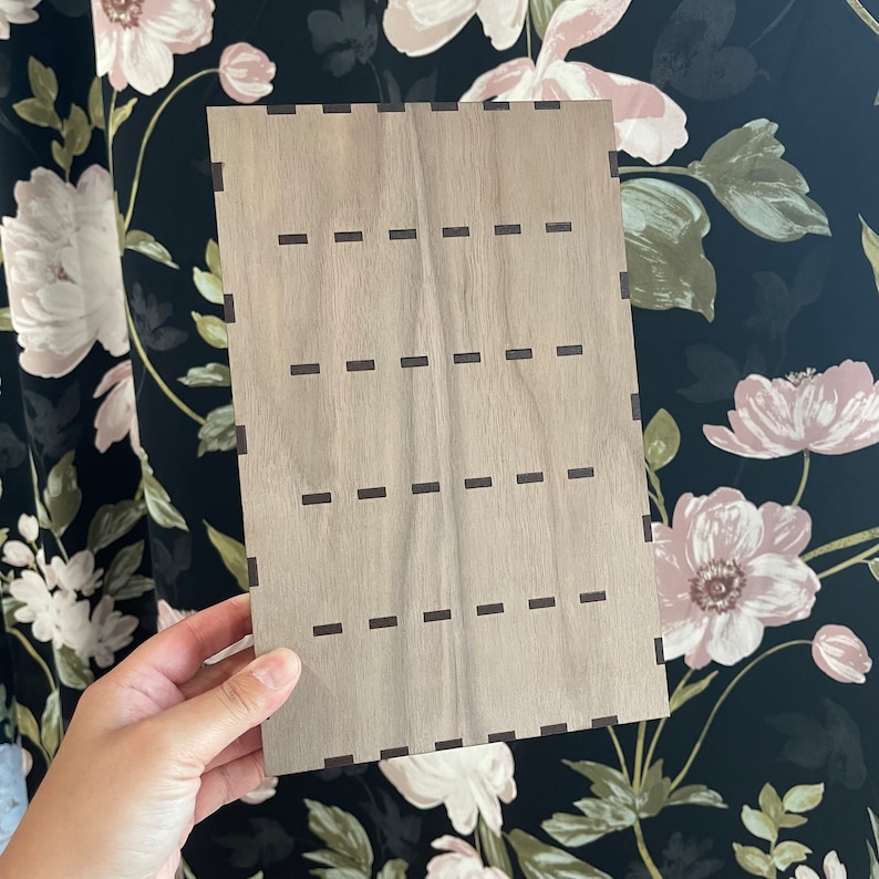 May include: A light brown wooden board with a grid of evenly spaced, dark brown lines.