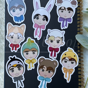 May include: Nine colorful stickers featuring cartoon characters wearing animal hats. Each character has a different animal hat, including a wolf, bunny, sheep, dog, dinosaur, penguin, bear, and chicken. Each character is wearing a bow tie.