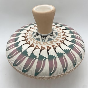 May include: A white ceramic vase with a wide base and a narrow neck. The vase is decorated with a geometric pattern in shades of brown, green, and purple.