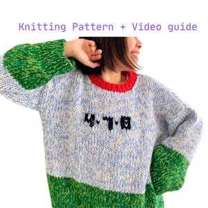 May include: A hand-knitted sweater with a blue and white speckled body, green sleeves and lower section, and a red neckline. The sweater features the text "M.T.B." in black. The words "Knitting Pattern + Video guide" are in the top of the image.