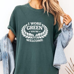 Peut inclure: T-shirt vert foncé avec l'inscription blanche "I WORE GREEN YOU'RE WELCOME" dans une couronne de laurier. Le t-shirt a des manches courtes et une coupe décontractée.