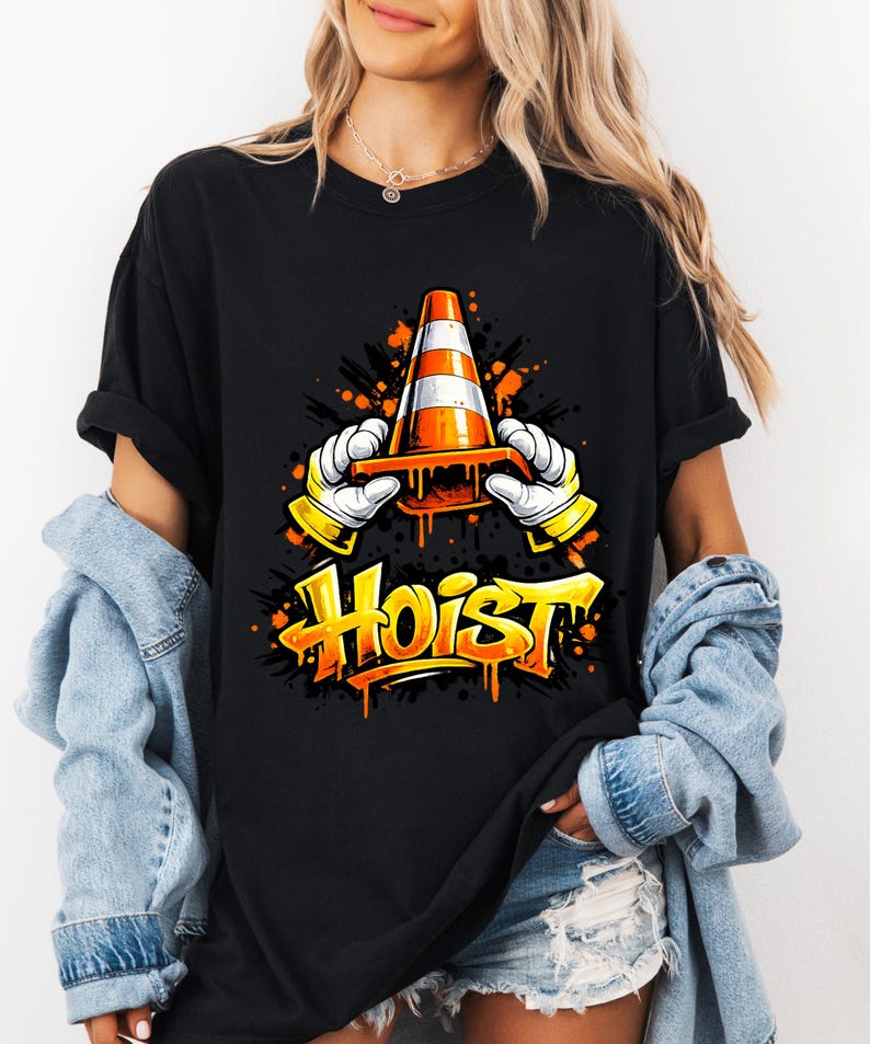 May include: Black t-shirt featuring a graphic of a traffic cone held by gloved hands, with the word "Hoist" in orange and yellow graffiti style. The design includes orange and black paint splatter effects.
