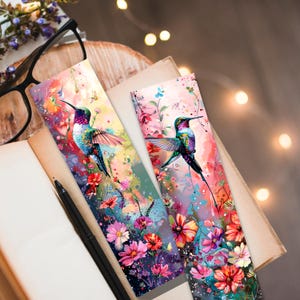 May include: Two colorful hummingbird bookmarks with a watercolor background and floral accents. The hummingbirds are flying with their wings spread. The bookmarks are perfect for book lovers and nature enthusiasts.
