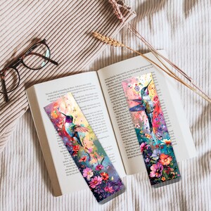 May include: Two colorful hummingbird bookmarks with floral designs. The bookmarks are made of metal and have a glossy finish.