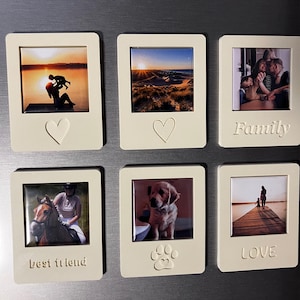 May include: Six off-white rectangular photo magnets. Each magnet holds a small photo and has a decorative element. One has a heart, one has a paw print, and one says "best friend", "family", and "love".