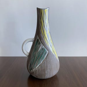 May include: A set of three ceramic mugs with a speckled, matte finish in cream, light grey, and dark grey. Each mug has a simple, minimalist design and a rounded handle.