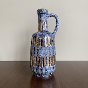 May include: A blue and gold ceramic vase with a geometric pattern. The vase has a wide mouth and a narrow neck, and it is decorated with gold stripes.