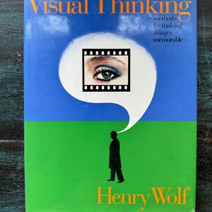 May include: A book titled "Visual Thinking" with orange text on a blue and green background. The cover features a film strip with an eye inside a white thought bubble, and a silhouette of a person. The author's name, Henry Wolf, is at the bottom.