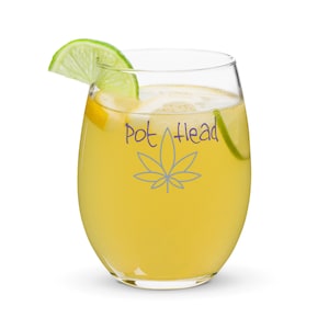 May include: A clear glass with a yellow beverage and a lime wedge. The glass has a marijuana leaf and the text "Pot Head" printed on it.