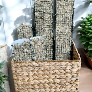 Peut inclure: Un ensemble de quatre panneaux en treillis métallique vert remplis de mousse séchée, empilés dans un panier en osier tressé.