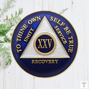 May include: A blue and white sobriety medallion with the words "To Thine Own Self Be True" and "Unity, Service, Recovery" around a triangle. The number "XXV" is in the center of the triangle.