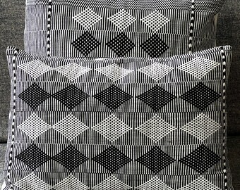 Puede incluir: Dos cojines decorativos de color blanco y negro con un diseño geométrico de rombos. Los cojines están hechos de tela tejida con una superficie texturizada.