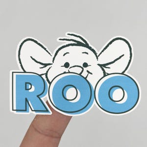 May include: A die-cut sticker featuring a black and white line drawing of a cartoon kangaroo character with large ears peeking over the bold, light blue capital letters that spell out the name ROO in a sans-serif font with a dark outline.