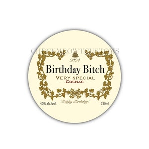 May include: A round, cream-colored label with gold accents and the text "Birthday Bitch" in black. The label also includes the text "Very Special Cognac", "2024", "40% alc./vol.", "Happy Birthday!" and "750ml".