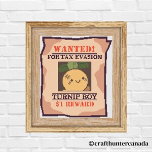 Op de afbeelding: Een ingelijst kruissteekkunstwerk met een "Wanted"-posterontwerp. De poster luidt "WANTED! FOR TAX EVASION" boven een afbeelding van een lachend knolgewas-personage. Daaronder staat "TURNIP BOY $1 REWARD". De lijst is lichtbruin.