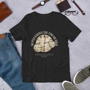 May include: A dark heather grey t-shirt with a vintage-style graphic of three clocks with the text "No Man Knows The Time Or Hour" and a bible verse from Mark 13:32.