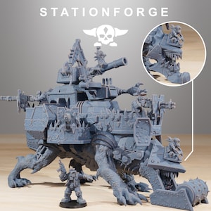 May include: A gray plastic model of a large, heavily armed, and armored vehicle with a skull and crossbones logo. The vehicle has a large cannon, multiple guns, and a claw-like arm. The vehicle is on a wooden surface.