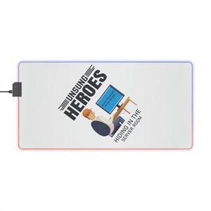 Può includere: Tappetino per mouse rettangolare bianco con bordo a LED colorato. Il tappetino presenta il testo "UNSUNG HEROES" e un'illustrazione di una persona al computer con il testo "HIDING IN THE SERVER ROOM".