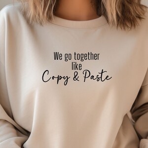 May include: A beige sweatshirt with the text "We go together like Copy & Paste" printed on the front.