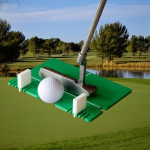 May include: A green putting green with a golf ball and putter on a putting practice mat. The mat has white plastic flags on either side of the ball.