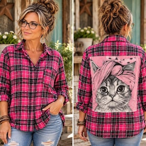 May include: A long-sleeve button-down shirt in a pink and black plaid pattern. The front features a standard collar and a chest pocket. The back displays a large, rectangular graphic print of a cat wearing a pink polka-dot head wrap.