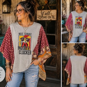 May include: A grey short-sleeve top with a graphic print of a chicken wearing sunglasses and the text NOT TODAY MOTHER CLUCKER. The garment features wide, loose-fitting sleeves with a dark red and orange floral pattern and a round neckline.
