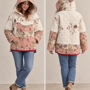 May include: A quilted hooded jacket featuring a cream-colored base with floral patterns in shades of pink, green, and brown. The garment includes a large front pocket, long sleeves, and a dark red trim along the bottom hem, shown from front and back.