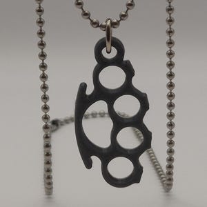 May include: A silver chain necklace with a black metal pendant shaped like a knuckle duster.