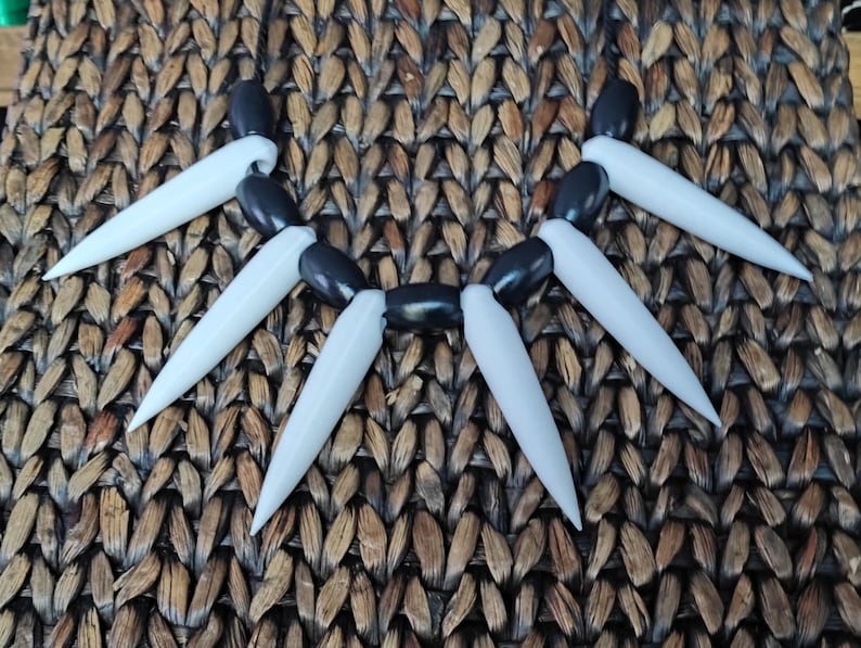 May include: A black and white necklace with white pointed spikes and black beads.