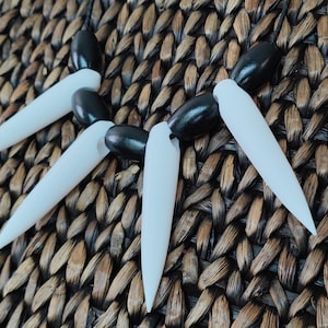 May include: A black and white necklace with sharp, pointed teeth-like pendants. The necklace is made of plastic and has a black cord.