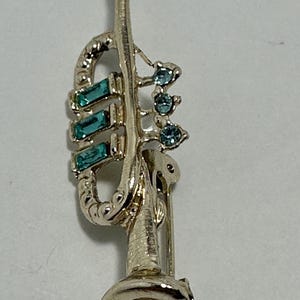 Vintage, silvertone trumpet brooch with aqua colored rhinestones. Unmarked