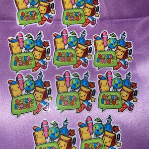 Op de afbeelding: Een verzameling kleurrijke stickers met een schoolthema. Elke sticker heeft een tekstballon met de tekst "BACK TO SCHOOL", samen met illustraties van een wereldbol, boeken, pennen en andere schoolbenodigdheden.