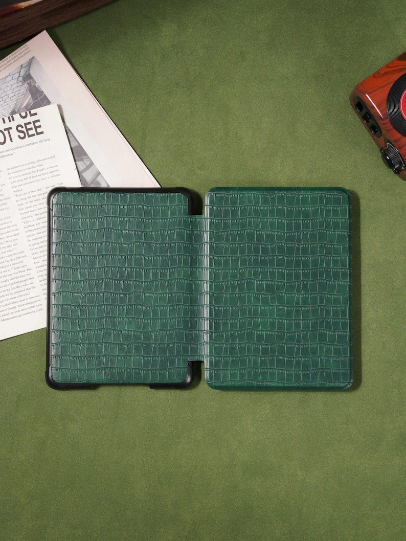 May include: Green faux-leather tablet case with a crocodile skin texture. The case is open, revealing the interior. The case has a black border and is set against a green background.