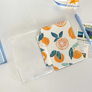 May include: A clear plastic case with a white and orange patterned case. The patterned case has a design of oranges and leaves. The case is open and the patterned case is on top of the clear case.