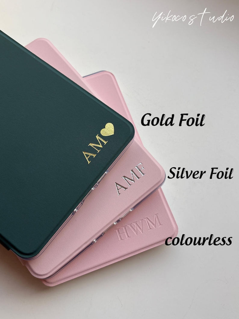 May include: Three rectangular cases in dark green and light pink with personalized monograms. The top case features gold foil initials AM with a heart, the middle case has silver foil initials AMF, and the bottom case has colorless embossed initials HWM.