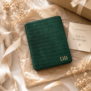 May include: A dark green rectangular e-reader case with a textured crocodile skin pattern and the gold embossed initials DB in the bottom right corner. A small square card is included with the text: Especially for you, Enjoy every beautiful chapter.