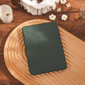 May include: A rectangular e-reader device with a solid dark forest green casing and a smooth, matte finish. The device features rounded corners and a flat, uniform surface, presented as a standalone electronic unit without any visible buttons or ports.
