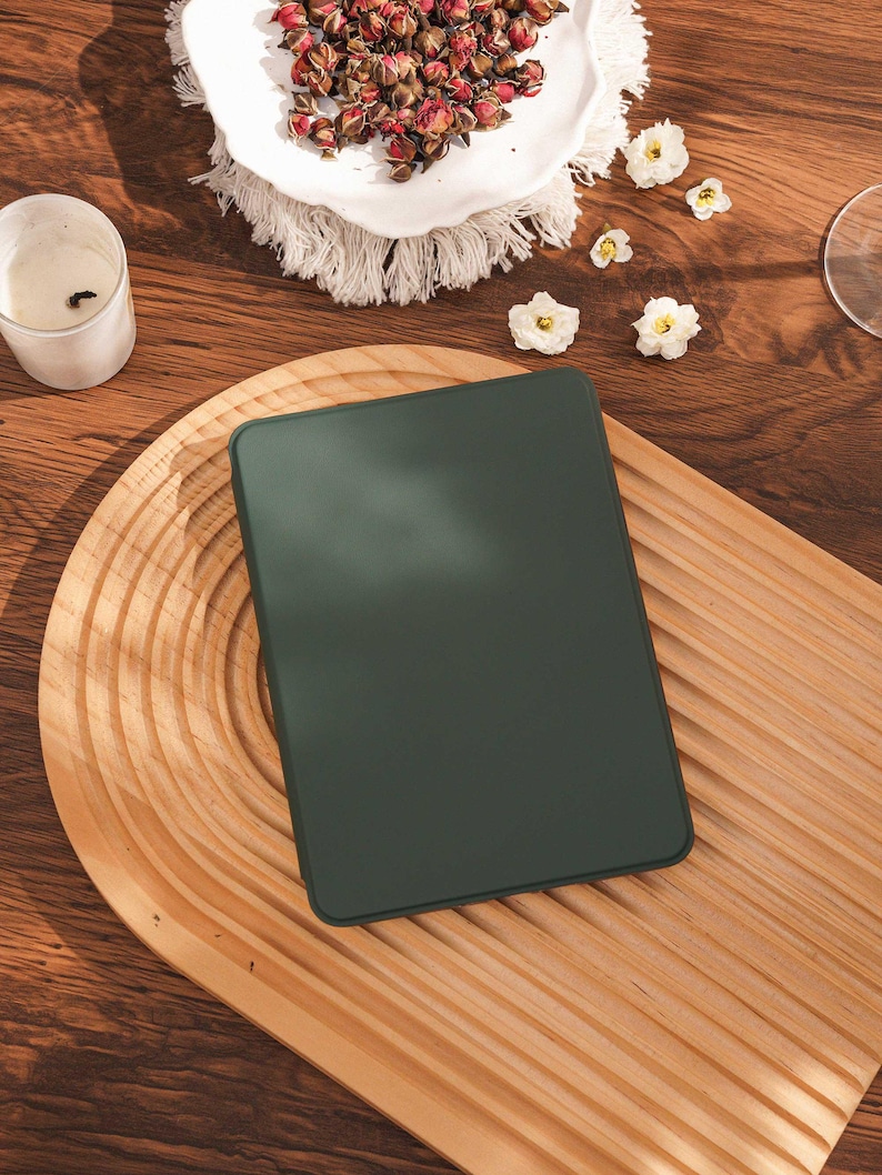 May include: A rectangular e-reader device with a solid dark forest green casing and a smooth, matte finish. The device features rounded corners and a flat, uniform surface, presented as a standalone electronic unit without any visible buttons or ports.