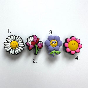 May include: Four colorful flower shoe charms with smiley faces. The charms are numbered 1 through 4.