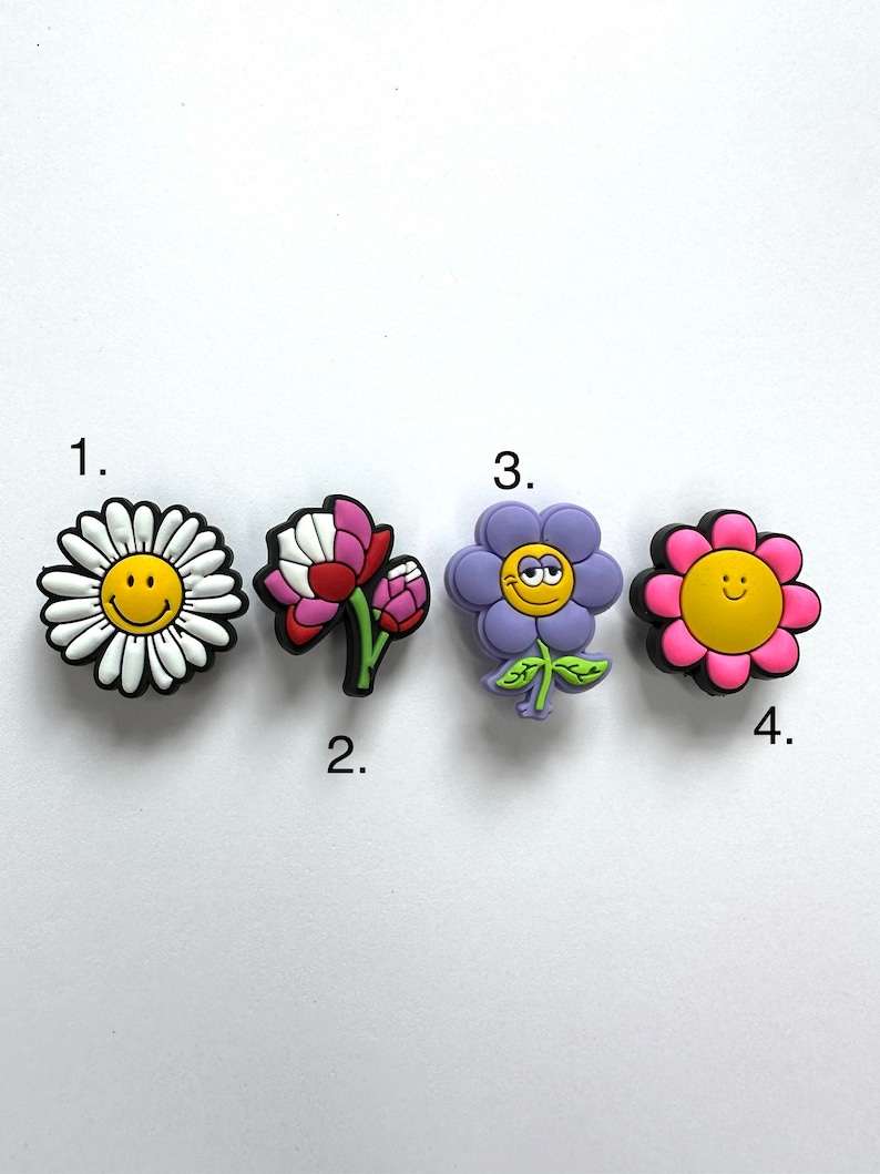 May include: Four colorful flower shoe charms with smiley faces. The charms are numbered 1 through 4.