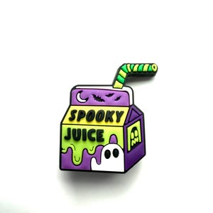 Op de afbeelding: Een Halloween-thema bedel in de vorm van een pakje sap. De doos is paars, groen en geel, met de woorden "SPOOKY JUICE" in het zwart. Een witte geest en een groen rietje maken het ontwerp compleet.