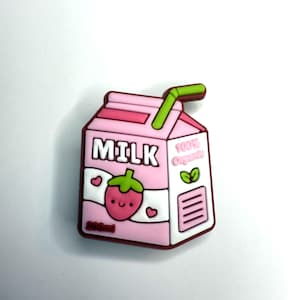 May include: A pink and white milk carton with a strawberry design. The carton has a green straw and text that reads "MILK" and "100% Organic". The carton also has a cute strawberry graphic and heart details.